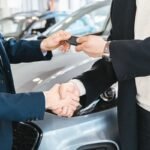 Lease vs buy a car in 2026 — new car keys being handed over at a dealership